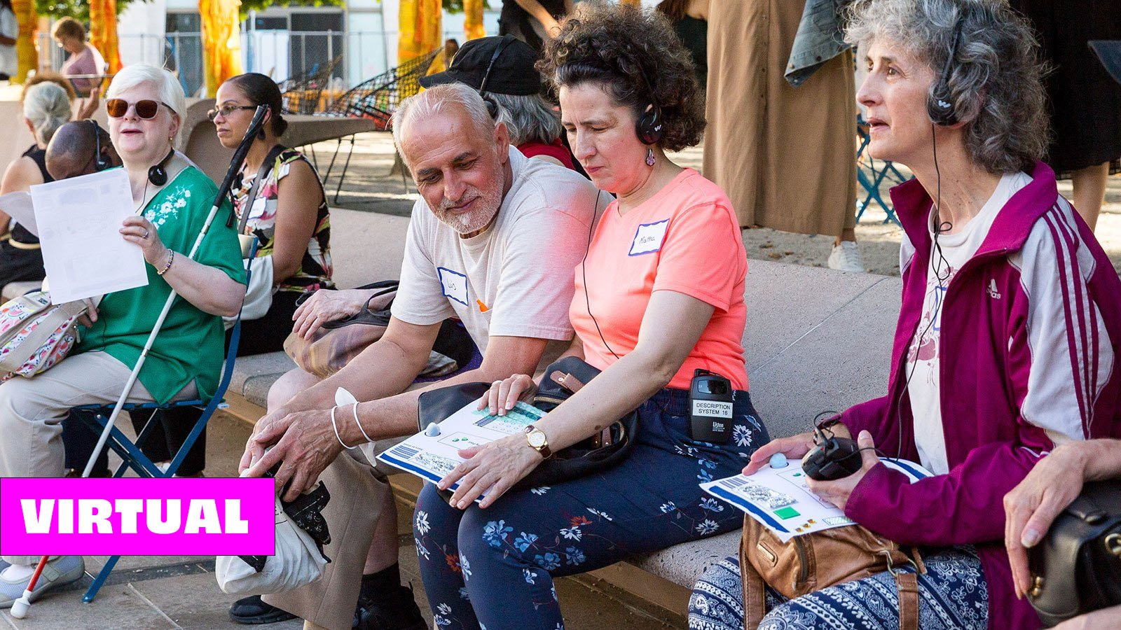  People in colorful outfits sit on a bench holding tactile maps and wearing headphones listening to a verbal description tour.